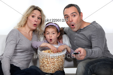 parents-daughter-watching-tv-eating-popcorn-ph122901275.jpg